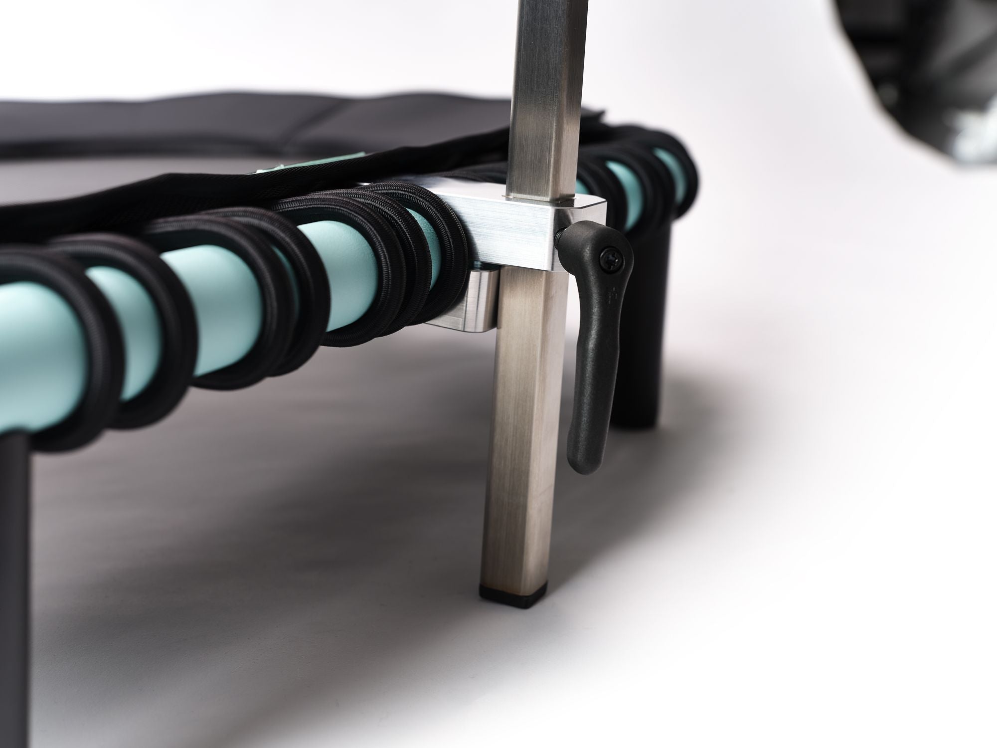 Detailaufnahme der Standpolin Halterung mit silbernem Befestigungsblock, schwarzem Feststellhebel, Aqua Rahmen und schwarzen Gummiseilen.