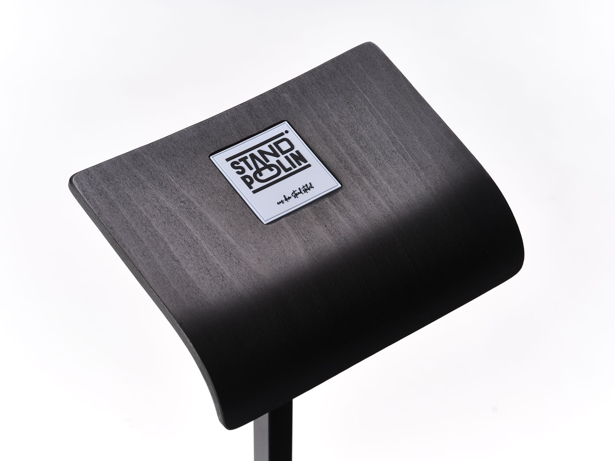 Detailaufnahme der gebogenen schwarzen Standpolin Sitzfläche mit sichtbarem Standpolin Logo, Holzstruktur und stabilem Standfuß auf weißem Hintergrund.