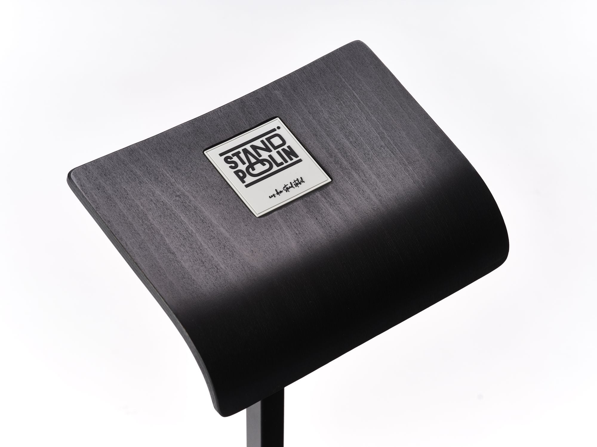 Detailaufnahme der gebogenen schwarzen Standpolin Sitzfläche mit cremefarbigen Standpolin Logo, sichtbarer Holzstruktur und stabilem Standfuß auf weißem Hintergrund.