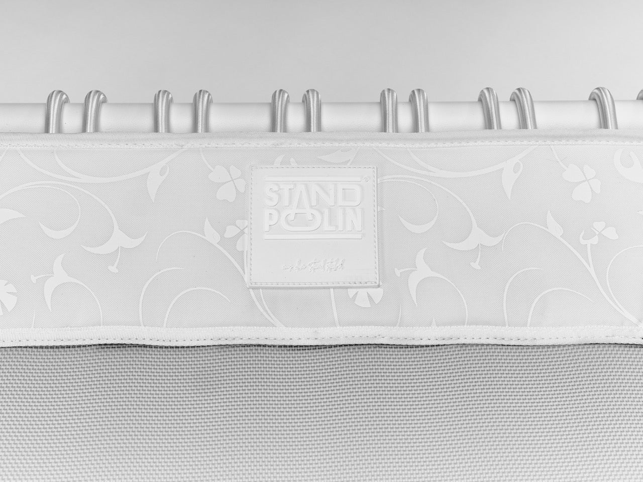 Standpolin in Weiß im Detail mit geprägtem Logo, floralem Randdesign, heller Sprungfläche und weißen Seilringen für aktives Stehen und Balance.