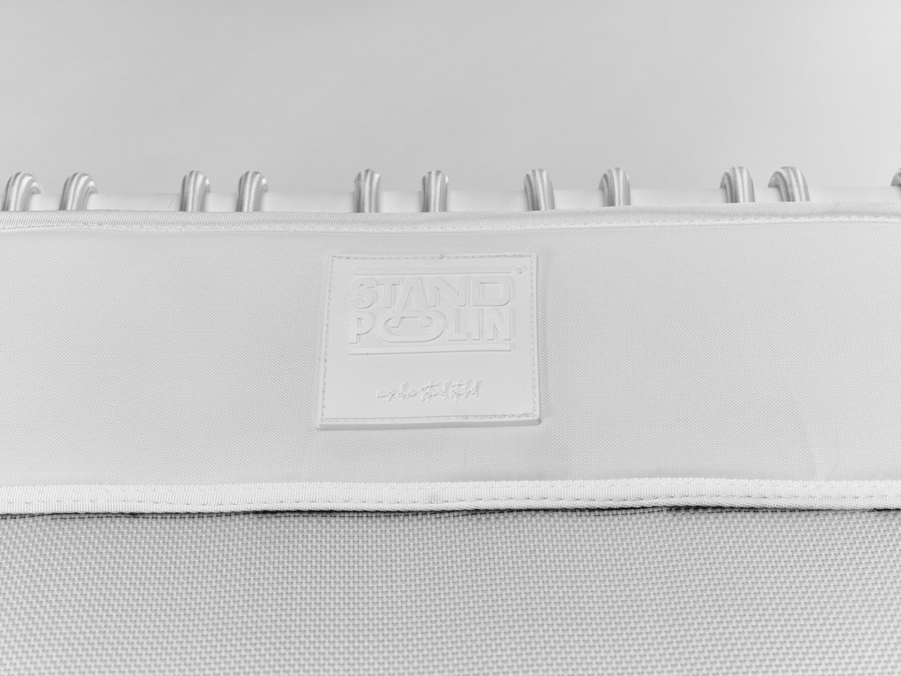 Standpolin in Weiß im Detail mit geprägtem Logo, heller Sprungfläche und weißen Seilringen für aktives Stehen, Balance und ergonomische Bewegung.