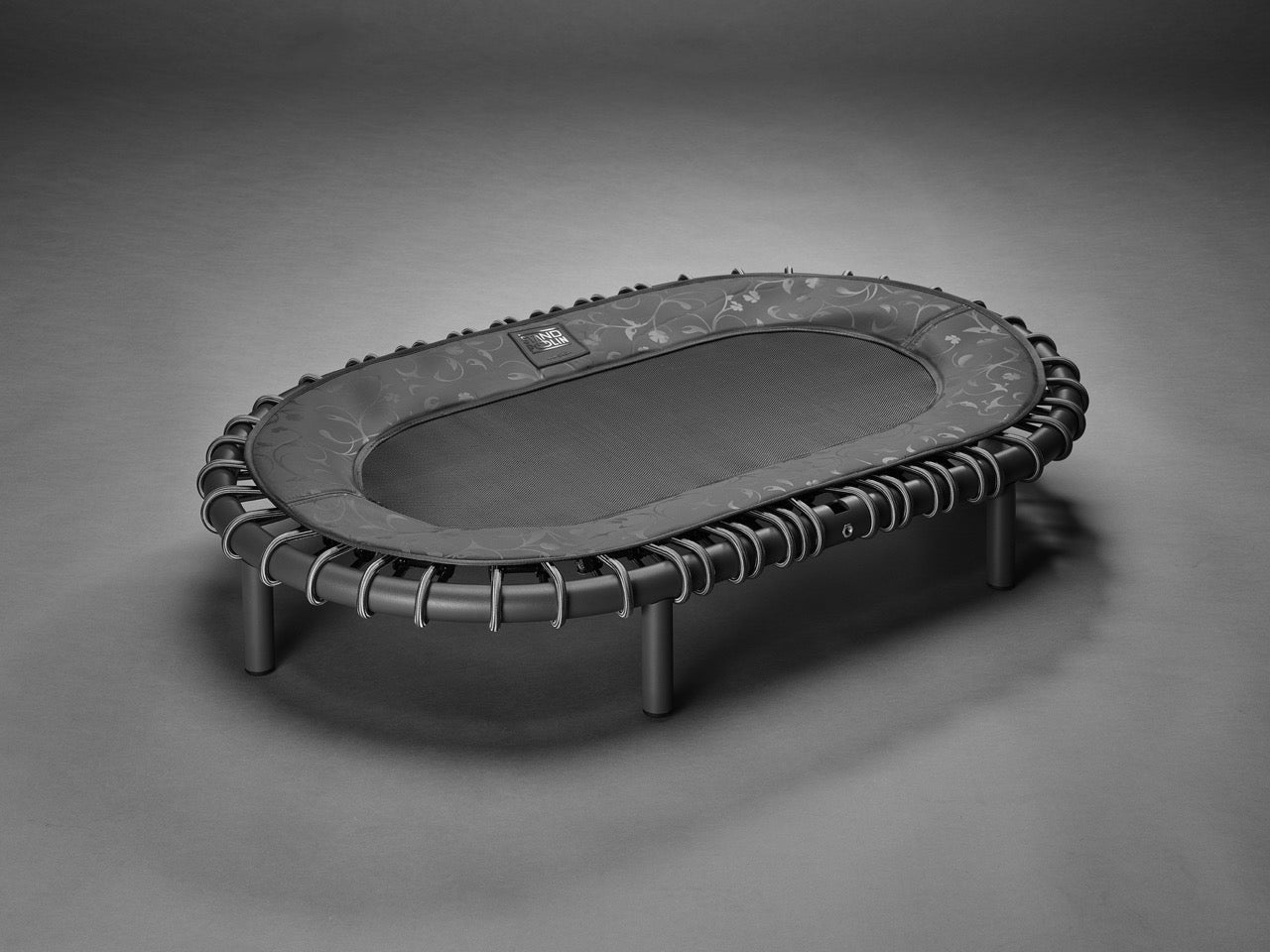Standpolin in Schwarz mit floraler Musterung, dunkler Sprungfläche, schwarzem Rahmen und Seilringen für aktives Stehen, Balance und ergonomische Bewegung.